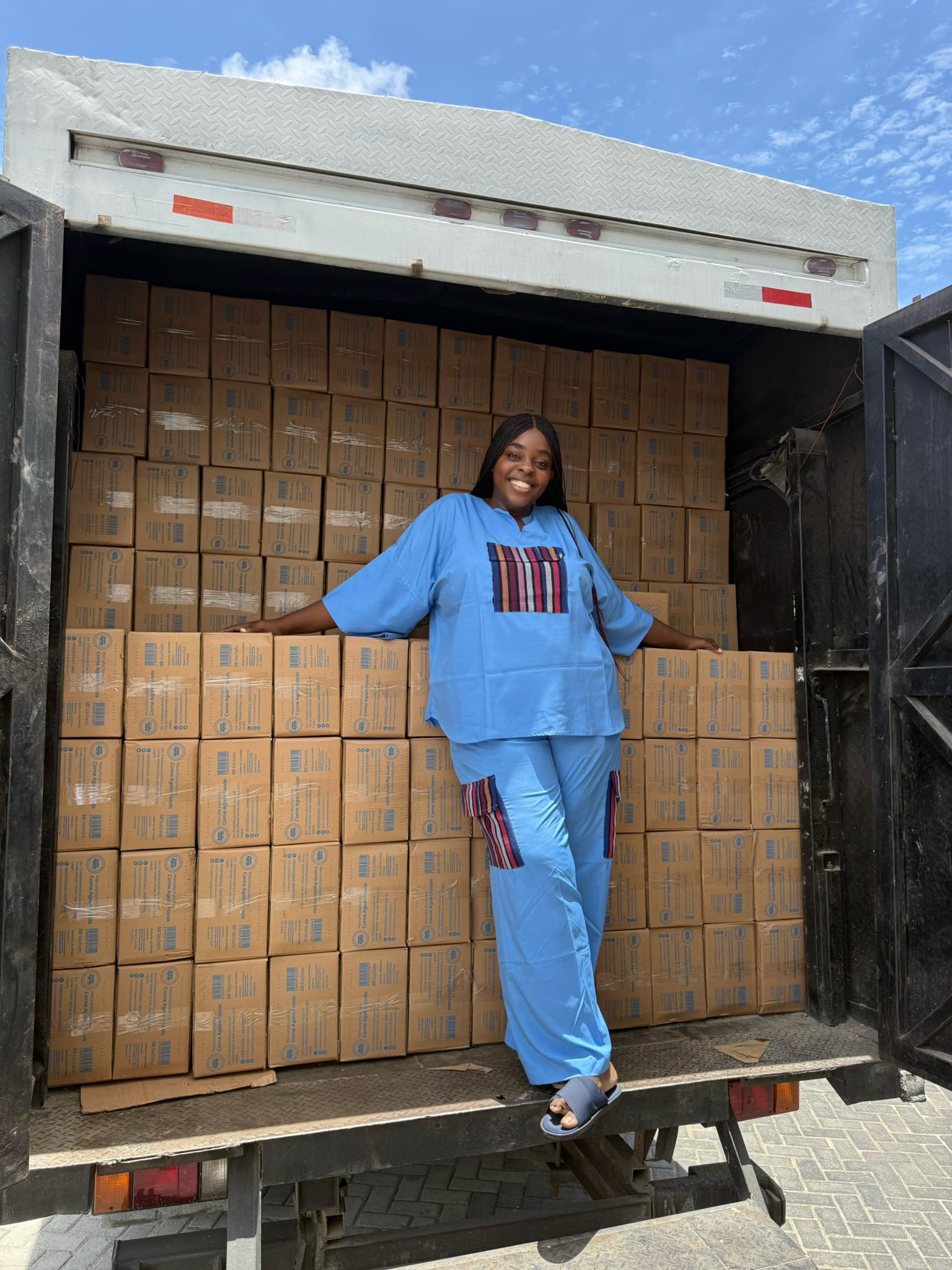 Nelly Agbogu standing in a truck loaded with cartons of Tapiokies